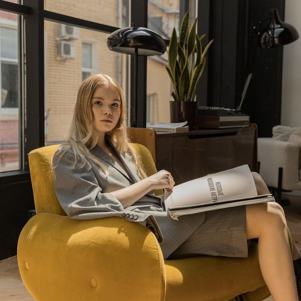 Person sitting comfortably on a cushion by a sunlit window.